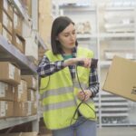 Woman store worker scans the product barcode scanner in the warehouse